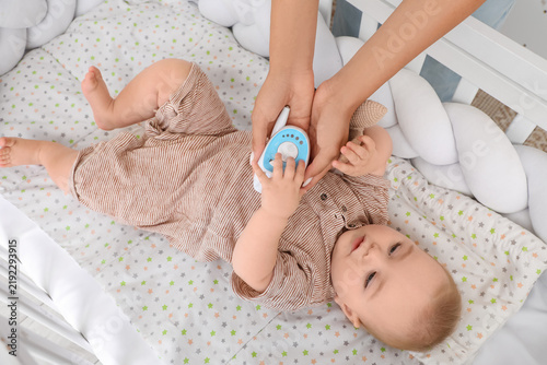 Female hand with radio nanny and cute little baby lying in crib at home