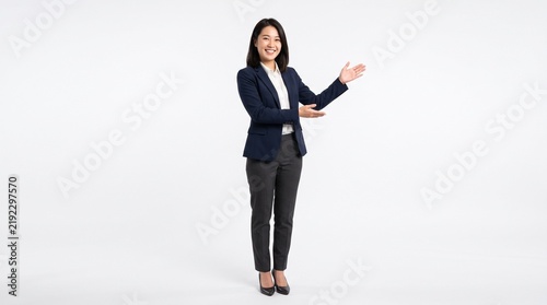 Smiling Asian businesswoman in corporate suit standing and presenting gesture isolated on white background