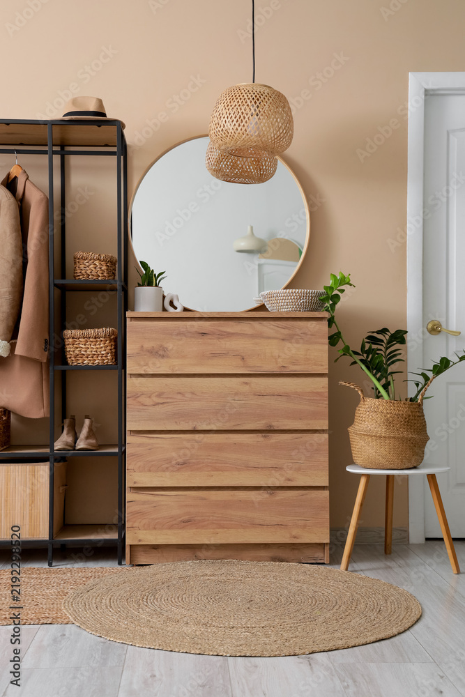 Obraz premium Interior of stylish hallway with coat rack, mirror and wicker baskets