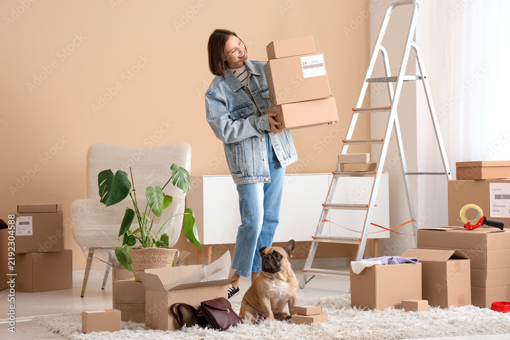 Fototapeta premium Pretty young woman with cute French bulldog and parcels at home