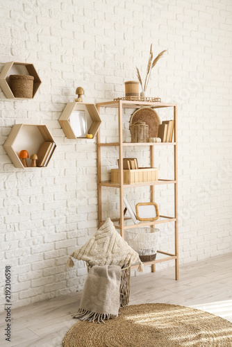 Shelving unit with books, mushrooms and pampas grass near white brick wall