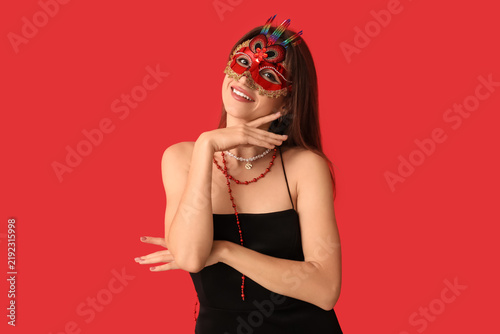 Happy young woman in carnival mask on red background