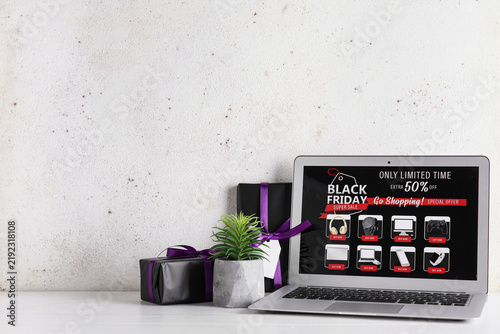 Laptop with Black Friday gadgets sale advertisement and gift boxes on white t...