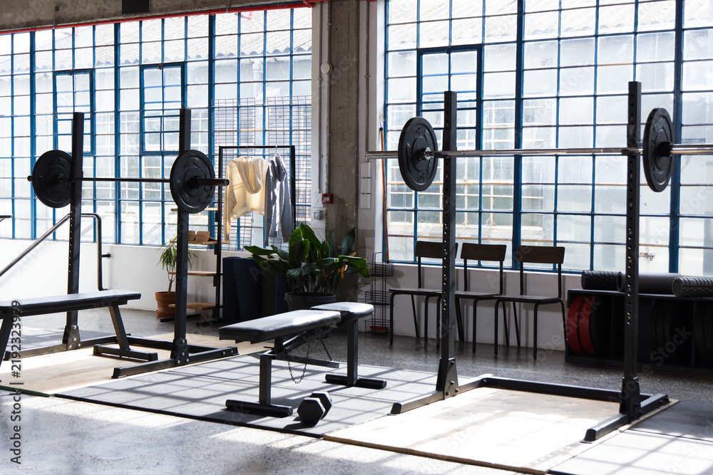Obraz premium Center weight setup occupying space with bench and loaded barbells on lifting platform in warehouse