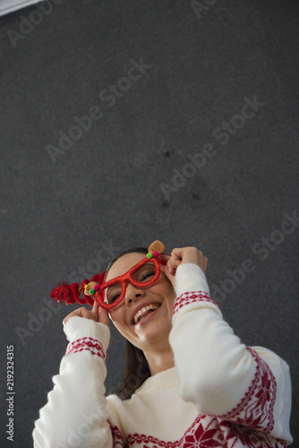 Photography Female adjusting festive red novelty glasses while smiling, wearing white knit s