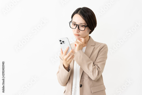 Фотография スマトフォンを使う眼鏡をかけたスーツ姿の女性