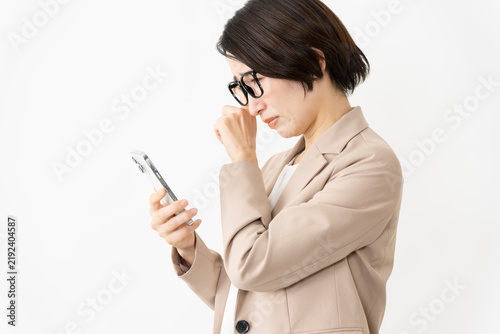 スマトフォンを使う眼鏡をかけたスーツ姿の女性