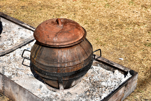Tapety artystyczne Traditional Clay Pot Cooking Over Open Embers Outdoors