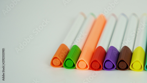 A collection of colorful markers with white barrels and colorful caps, isolated on a white background, children's school supplies for coloring.