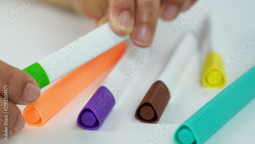 Cuadro en lienzo A woman's hand is capping a green marker, set against a background of assorted colorful markers—children's school supplies for coloring