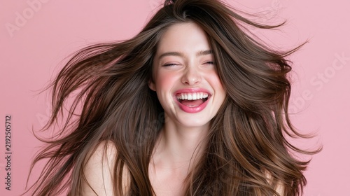 Joyful woman with flowing hair laughs exuberantly against a pastel backdrop.