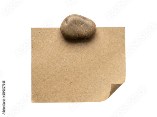 Fotografie Brown kraft paper sheet held down by smooth river stone isolated on transparent