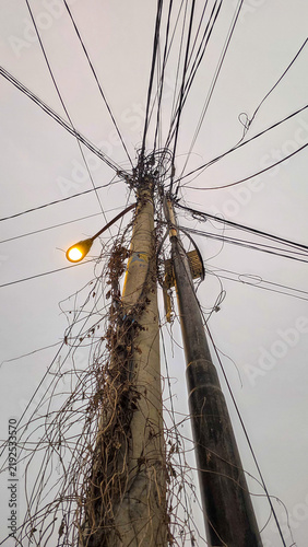Foto Tangled web of power and communication lines on urban utility poles, entwined wi