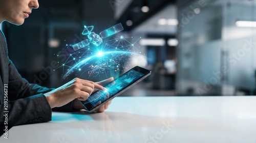 Woman using tablet with futuristic holographic interface showing global network and satellite