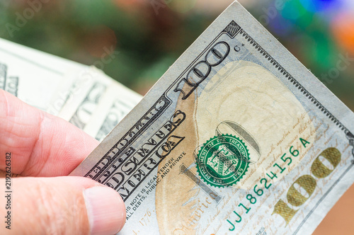 Картината върху платно Close-up of a hand holding a one hundred US dollar bill with other banknotes in