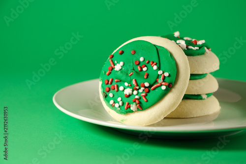 Frosted sugar cookies on a white plate against a green background