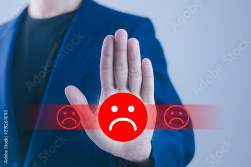 Bild auf Leinwand Business professional showing a stop hand gesture with a sad face icon, symbolizing negative feedback, customer dissatisfaction, rejection, poor service, complaints, and brand reputation concerns now
