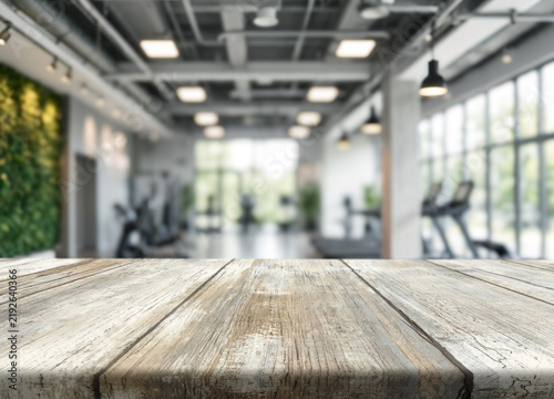 Fotografía Wood tabletop sits in bright gym studio with blurred workout equipment beyond