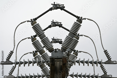 Wooden Crossarm with Disc Insulators and Fuse Cutouts, Diagonal View Against Overcast Sky