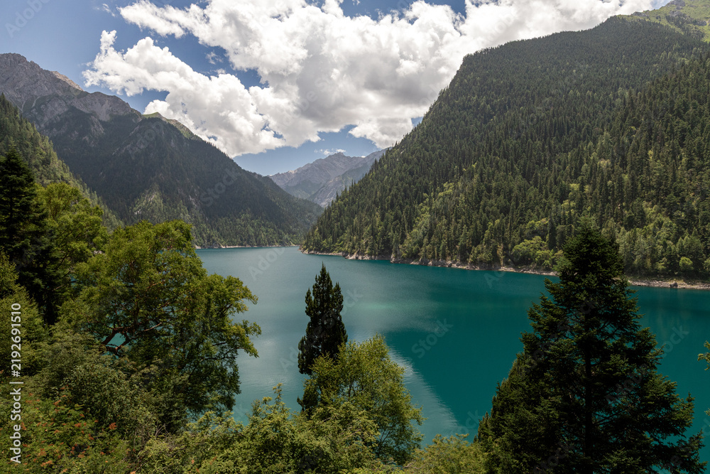Obraz premium Turquoise Mountain Lake Surrounded by Forested Peaks in Jiuzhaigou, China