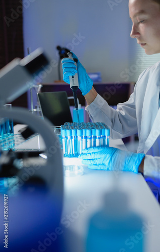 Obraz na plátně Scientist pipetting liquid into test tubes in laboratory