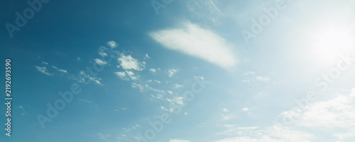 the sky is clear blue with fluffy white clouds, the sky is very bright, and the sun shines.