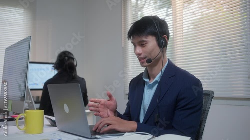 Competent call center agent providing customer support with headset and laptop in a modern office environment
