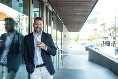 Businessman drinking coffee outside office building