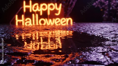A vibrant orange neon 'Happy Halloween' sign reflects brightly in a dark, wet puddle on a textured surface at night, creating an eerie glow.