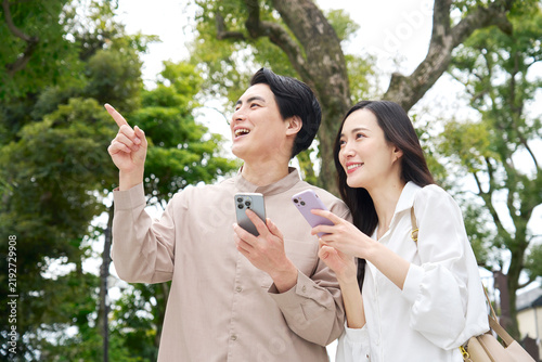 Fotografía 公園でスマホを持って話す笑顔のカップル30代