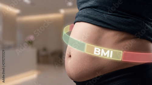 Overweight obesity and BMI concept with measuring tape around bare abdomen showing body fat and health concern in indoor setting with emotional body image awareness