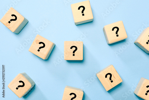 Scattered wooden blocks with question mark symbols represent questions, uncertainty, problem solving, curiosity, confusion, decision making, FAQ, and searching for answers. concept.