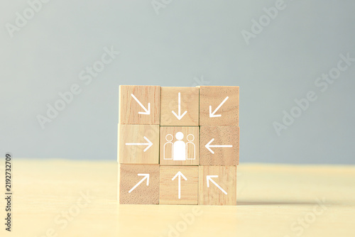 Wooden blocks with arrows pointing toward a team icon represent teamwork, recruitment, leadership, collaboration, human resources, organizational focus, and people-centered strategy.