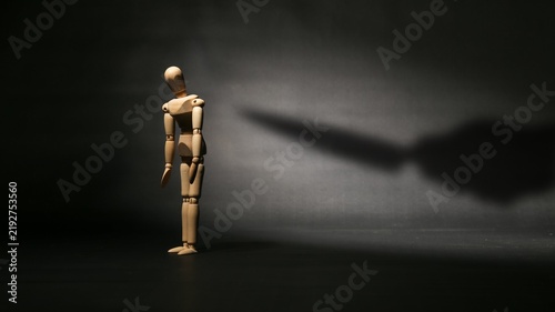 Foto Sad wooden mannequin standing alone with a knife shadow pointing at its back, symbolizing betrayal, backstabbing, or hidden danger
