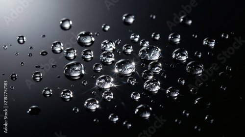 Fotografie Sparkling water droplets on a dark reflective surface, creating an abstract back