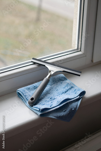 Fotografie Window squeegee and folded microfibre cloth on an apartment window sill