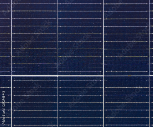 Close-up of dark blue photovoltaic solar cells with fine conductive lines and a geometric grid pattern on a solar panel