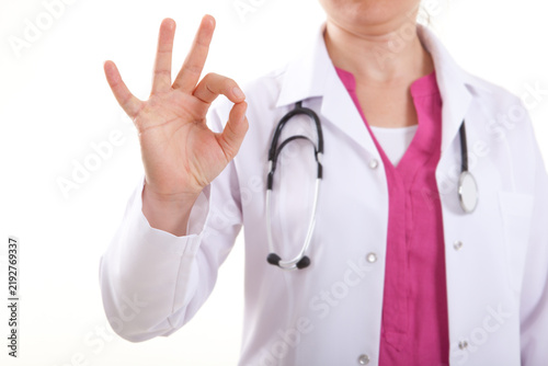 Close up of female doctor or nurse in lab coat showing OK sign isolated on white background.