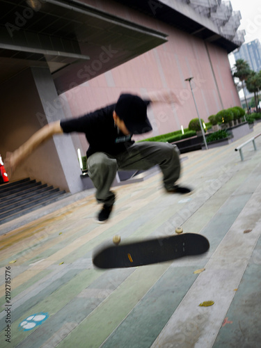 Quadro su tela A male skateboarder with a black shirt and cap doing a kickflip on a skateboard