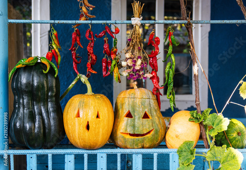 Rustic Homemade Halloween Decoration with Carved Pumpkins and Peppers, red and green chili peppers, dried flowers, and autumn foliage.