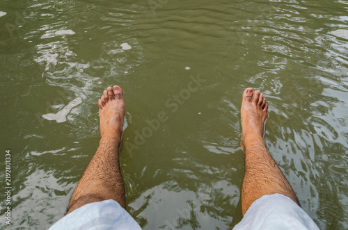Fotografie Feet of a Southeast Asian male teenager when he was sitting by the river in Nakh