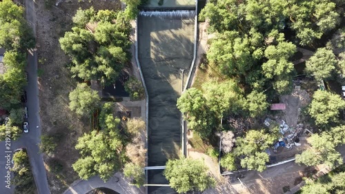 Top-down aerial view of river promenade park and dam infrastructure at early morning