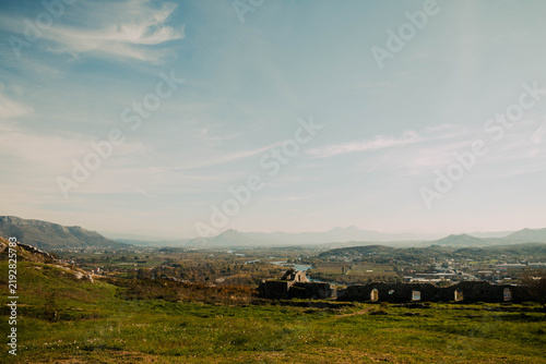 Photography A grassy hillside overlooking a broad river valley with historic ruins and dista