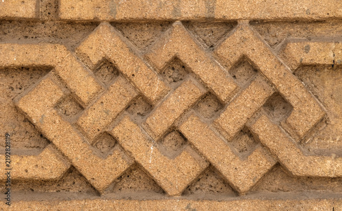 Bild auf Leinwand Oriental carved earthen wall with geometric motif and rough grain texture, ideal as a natural decorative background