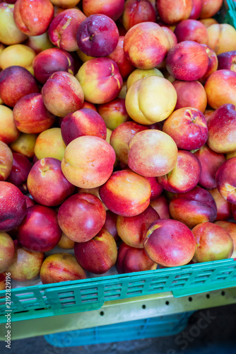 Foto Fresh ripe nectarines with smooth red and yellow skins fill a green crate at a market in South Korea