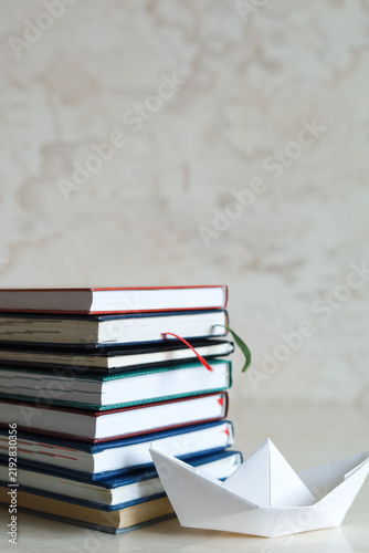 Konstfotografi Stack of closed books stands against a neutral wall with generous copy space