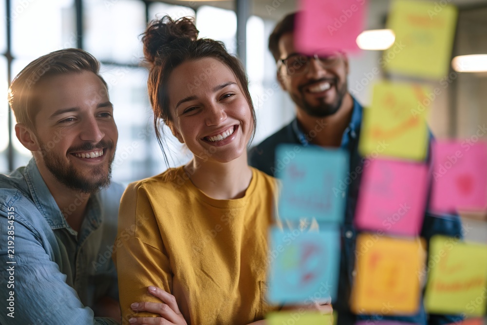 Obraz premium Professional diverse startup team brainstorming around a transparent glass board filled with colorful business strategy notes