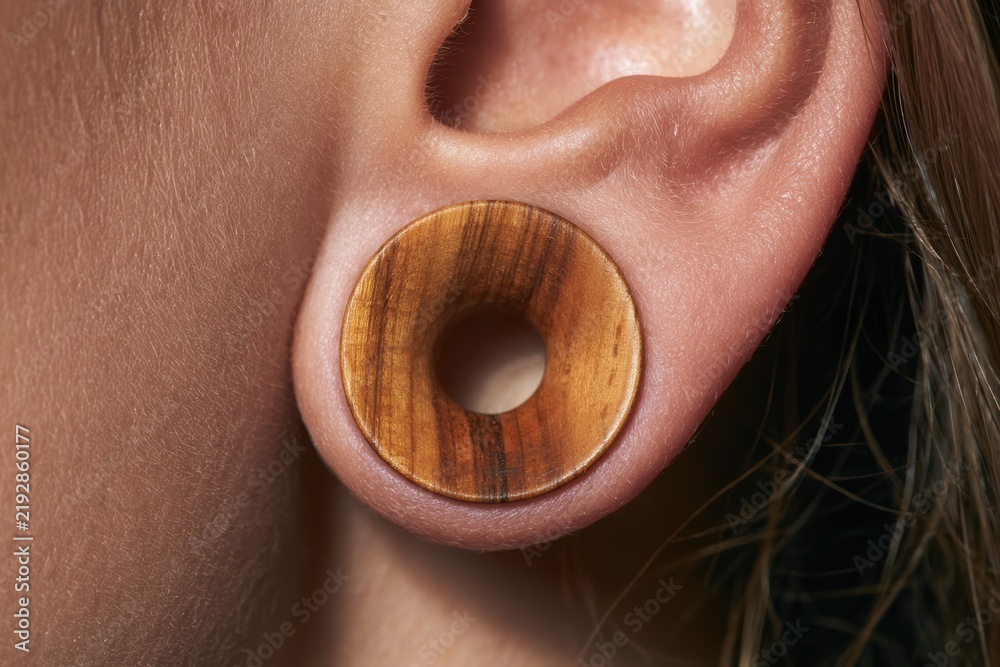 Fototapeta premium Human earlobe with a stretched piercing wearing an organic olive wood tunnel plug