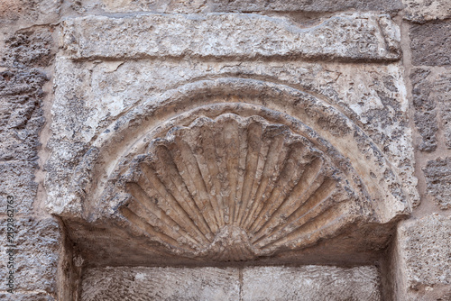 Fotografie Semicircular shell relief carved into calcarenite showing radiating flutes, diagenetic alteration, carbonate dissolution, and erosion patterns typical of historic Mediterranean ornamentation