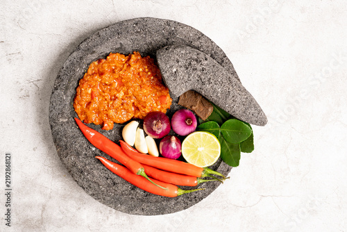 Indonesian red chilli paste on the stone mortar and pestle .